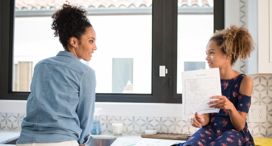 Mother and daughter near a kitchen window with an ADT security sensor